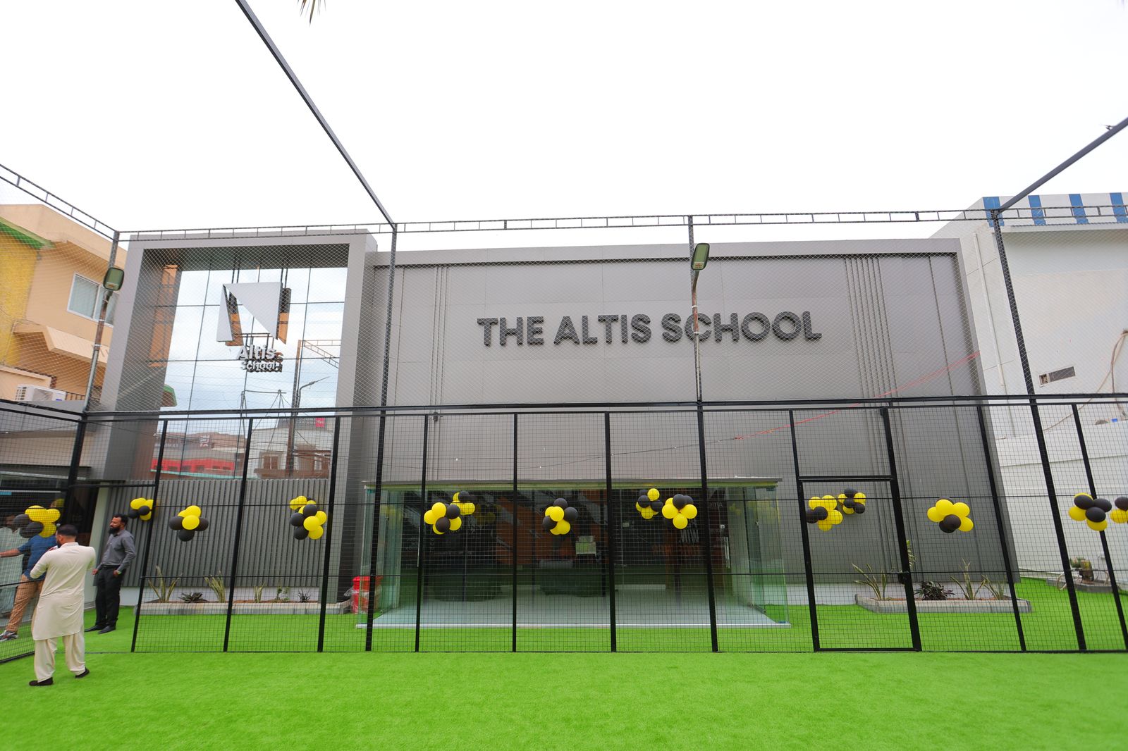 Front facade of The Altis School with branded glass entrance and outdoor turf